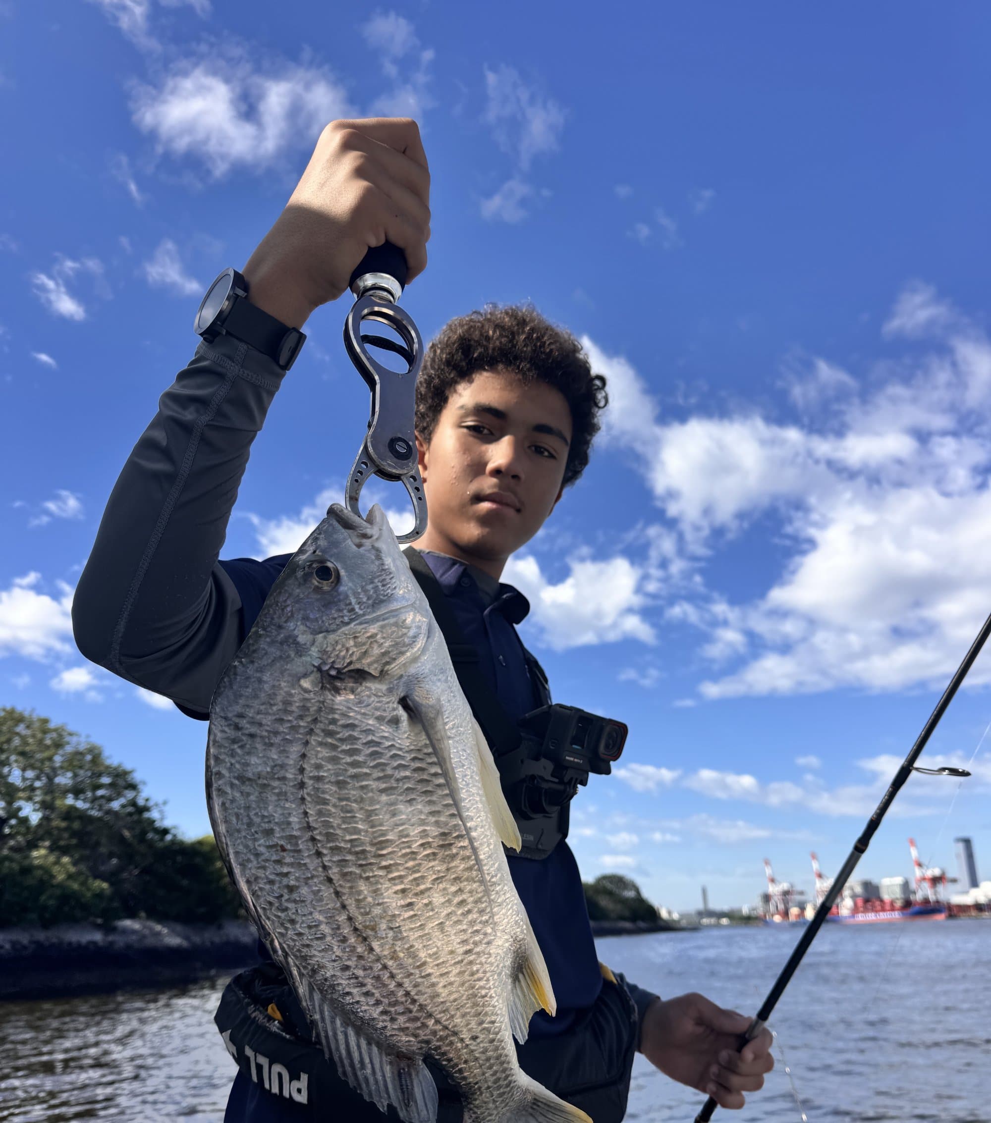 Reyaan holding up a fish he caught, on a boat on the water